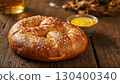 Close-up of traditional large salted soft pretzel with mustard dip on wooden table. Rustic Oktoberfest presentation. Traditional Bavarian beer snack concept with warm festive atmosphere, no people. 130400340