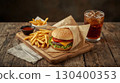 A delicious burger with cheddar cheese, lettuce, tomato, and a sesame seed bun, served with French fries and a cold glass of cola on a rustic table. National Cheeseburger Day, fast food concept. 130400353