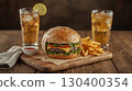 A cheeseburger with cheddar cheese, lettuce, and tomato in a sesame seed bun, served with French fries and a glass of iced tea with a slice of lemon. National Cheeseburger Day, fast food concept. 130400354