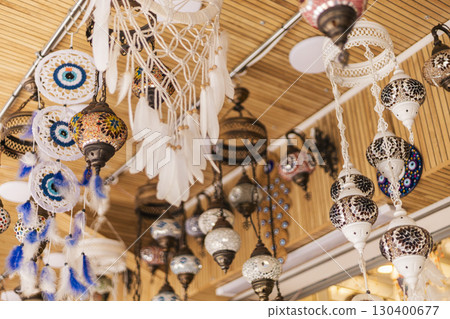 Various handmade ornaments and decorations dangle from the ceiling, displaying intricate designs and vibrant colors in a lively marketplace that celebrates local craftsmanship Various handmade ornaments and decorations dangle from the ceiling, displaying intricate designs and vibrant colors in a lively marketplace that celebrates local craftsmanship 130400677