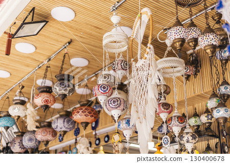 A variety of intricately designed lanterns and crafts hang from the ceiling in a bustling market in Morocco, attracting shoppers with their vivid colors and unique patterns 130400678