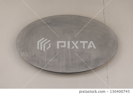 Minimalist blank concrete oval signboard mounted on wall. Rough textured cement surface ideal for mockups, design presentations, branding, signage, or architectural background concepts 130400745