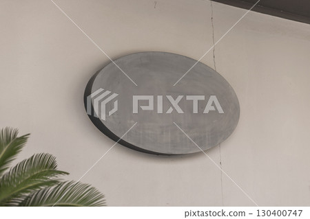 Minimalist blank concrete oval signboard on wall. Rough textured cement surface ideal for mockups, design presentations, branding, signage, or architectural background concepts 130400747