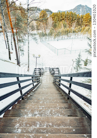 wooden staircase descending through snowy forest landscape with view of winter sports field and mountains in background, rustic outdoor structure, travel, adventure and seasonal nature wooden staircase descending through snowy forest landscape with view of winter sports field and mountains in background, rustic outdoor structure, travel, adventure and seasonal nature 130401020