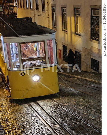 Vintage yellow tram navigating cobblestone streets at night in Lisbon, showcasing urban charm and historic transportation in a vibrant city atmosphere. Elevador da Gloria, Gloria funicular, Lisboa Vintage yellow tram navigating cobblestone streets at night in Lisbon, showcasing urban charm and historic transportation in a vibrant city atmosphere. Elevador da Gloria, Gloria funicular, Lisboa 130401050