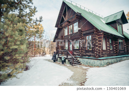wooden log house with green roof in snowy winter forest with people near entrance, rustic cabin architecture and concept of countryside vacation in cold season wooden log house with green roof in snowy winter forest with people near entrance, rustic cabin architecture and concept of countryside vacation in cold season 130401069