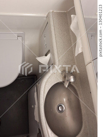 A restroom of airplane features a minimalistic design with a sink next to a toilet, displaying clean surfaces and ample lighting, suitable for public use at any time A restroom of airplane features a minimalistic design with a sink next to a toilet, displaying clean surfaces and ample lighting, suitable for public use at any time 130401213