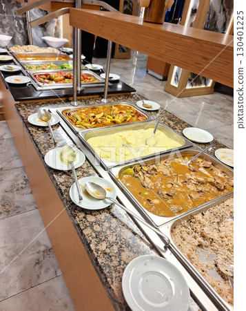 A lavish buffet setup showcases a variety of dishes and sides in a modern venue. Guests can select from colorful salads, hearty entrees. All inclusive 130401225