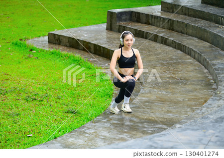 Female athlete in black sportswear warming up before workout, exercising with determination Female athlete in black sportswear warming up before workout, exercising with determination 130401274