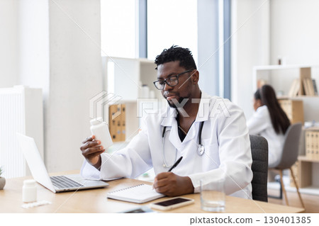 Male doctor reviewing medication information at office workplace. Medical professional with stethoscope writing prescription medication details. Healthcare provider analyzing explaining treatment plan Male doctor reviewing medication information at office workplace. Medical professional with stethoscope writing prescription medication details. Healthcare provider analyzing explaining treatment plan 130401385