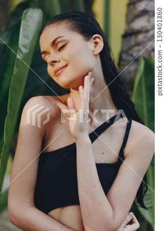 Tropical Paradise Stunning Young Woman in Black Bikini Posing in Front of Palm Tree Under the Sunlit Sky 130401860