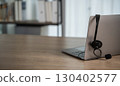 Laptop with headset on wooden desk, symbolizing 130402577