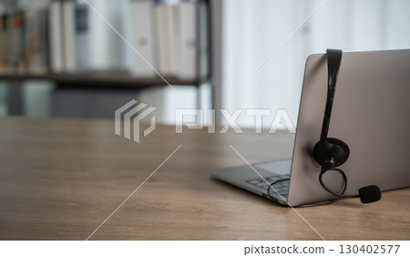Laptop with headset on wooden desk, symbolizing 130402577