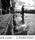 A working man waiting for a bus reflected in a puddle 130403565