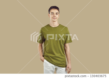 Young male model in casual wear posing with hand in pocket isolated on beige background 130403675
