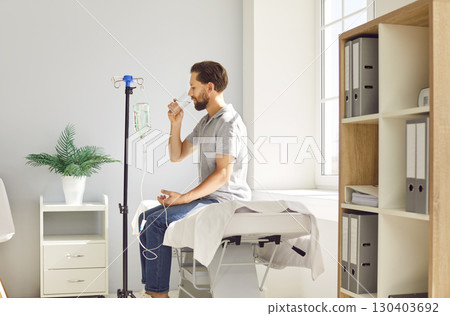 Man sitting at doctor's office in clinic while receiving IV drip infusion and vitamin therapy 130403692