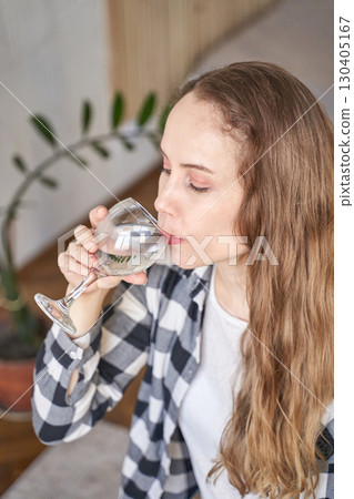 Young caucasian woman enjoying a glass of water at home 130405167