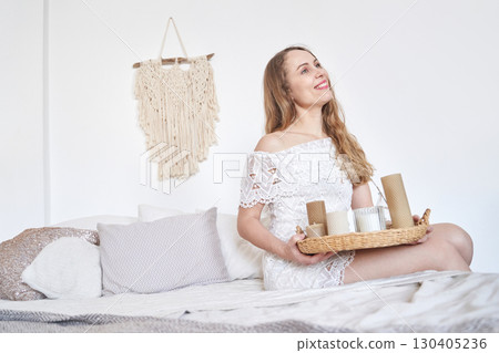 Young caucasian female smiling while sitting on bed with coffee tray in cozy Young caucasian female smiling while sitting on bed with coffee tray in cozy 130405236
