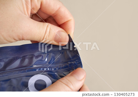 Caucasian adult opening resealable package with blue plastic zipper Caucasian adult opening resealable package with blue plastic zipper 130405273
