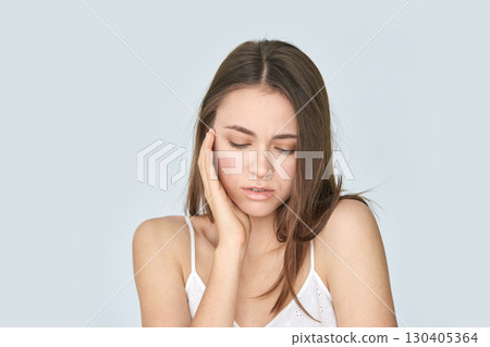 Young caucasian female with toothache holding jaw in painful expression Young caucasian female with toothache holding jaw in painful expression 130405364