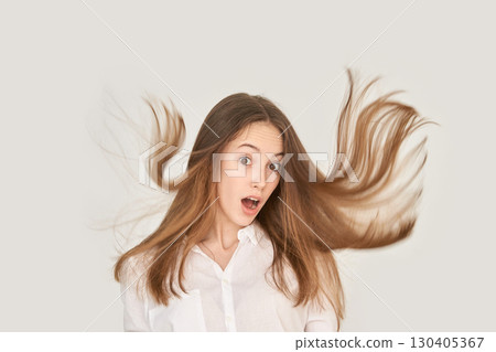 Surprised caucasian young female with long brown hair in motion against white Surprised caucasian young female with long brown hair in motion against white 130405367