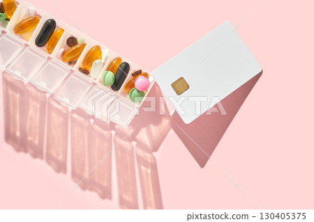 Weekly pill organizer and card on pink background 130405375