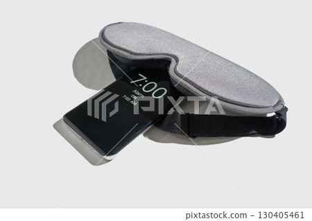 Sleep mask resting on smartphone displaying 7:00 am alarm time for morning Sleep mask resting on smartphone displaying 7:00 am alarm time for morning 130405461