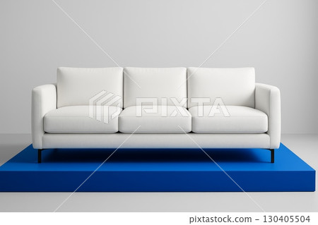 White modern sofa on blue platform against light grey wall in minimal interior, contemporary furniture front view 130405504