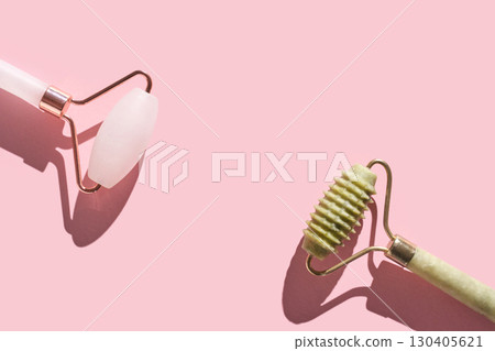 Beauty tools close-up: jade textured roller and rose quartz roller on pink Beauty tools close-up: jade textured roller and rose quartz roller on pink 130405621