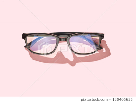 Black glasses with reflective lenses on pink background showing artistic shadow 130405635
