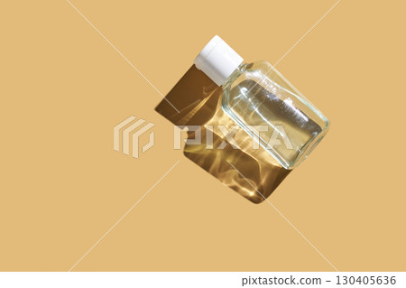 Transparent glass perfume bottle with white cap casting shadow on beige 130405636
