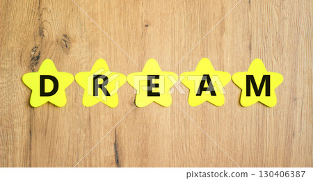 Dream symbol. Concept word Dream on beautiful yellow paper stars. Beautiful wooden table wooden background. Business lifestyle dream concept. Copy space. 130406387