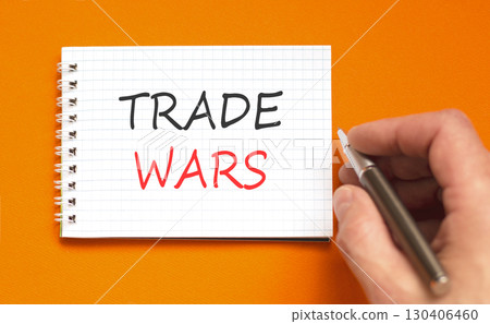 Trade wars symbol. Concept word Trade wars on beautiful white note. Businessman's hand with pen. Beautiful orange paper background. Business trade wars concept. Copy space. 130406460