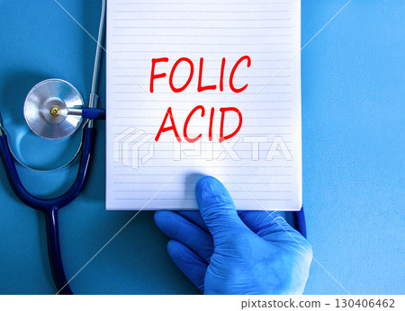 Folic acid symbol. Concept words Folic acid on beautiful white note. Doctor's hand in blue medical glove. Stethoscope. Beautiful blue background. Medical healthy lifestyle folic acid concept. 130406462