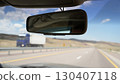 Rearview mirror reflecting car interior while overtaking truck on highway 130407118