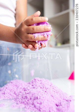 Child playing with purple kinetic sand indoors 130407276