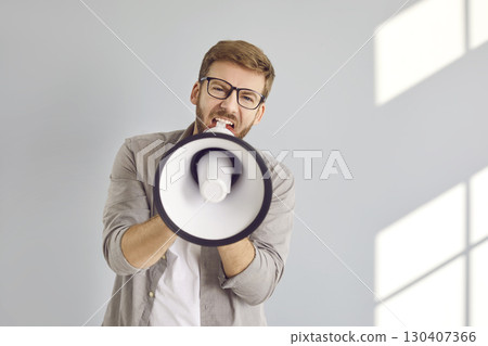 Man in glasses holding megaphone, asking for attention, screaming loudly, and sending message 130407366