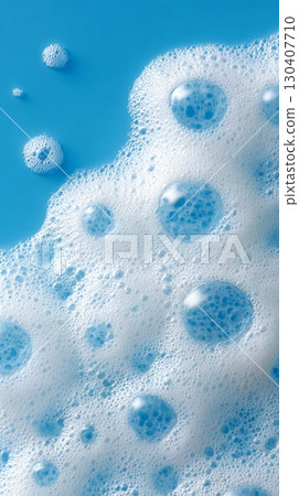 Foamy white bubbles on a bright blue surface close-up, abstract cleaning concept 130407710