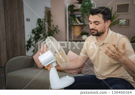 Man refreshing himself with a fan during a heat wave at home 130408164