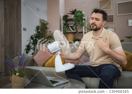 Man sweating at home refreshing himself with a fan during a heat wave Man sweating at home refreshing himself with a fan during a heat wave 130408165