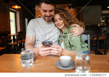 Happy couple looking at smartphone while having coffee in a cafe 130408177