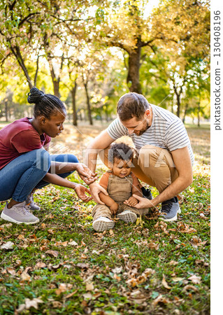 Parents enjoying quality time with their child in a park during autumn 130408196