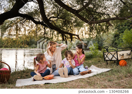 Happy family enjoying picnic by the river in the forest Happy family enjoying picnic by the river in the forest 130408266