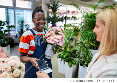 Florist holding flowers and accepting payment from customer using NFC technology Florist holding flowers and accepting payment from customer using NFC technology 130408331