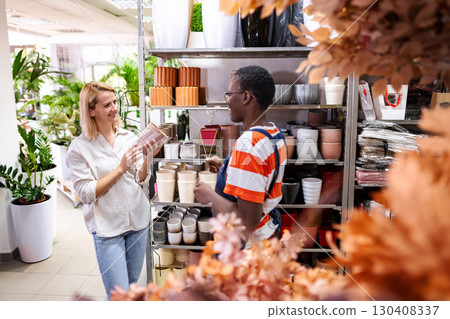 Woman choosing a flower pot while talking to the shop assistant 130408337
