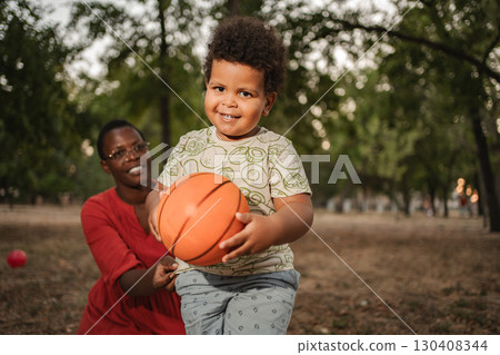 Happy toddler playing basketball with his mother in a park Happy toddler playing basketball with his mother in a park 130408344