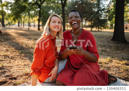 Two friends laughing while looking up in a park during sunset Two friends laughing while looking up in a park during sunset 130408351