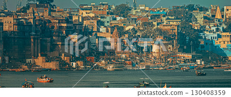 Varanasi, Uttar Pradesh, India. Boats Floating Near Rana Mahal Ghat, Darbhanga Ghat And Dashashwamedh Ghat In Early Morning. Many Hindu Temples. View From Riverbank Embankment Varanasi, Uttar Pradesh, India. Boats Floating Near Rana Mahal Ghat, Darbhanga Ghat And Dashashwamedh Ghat In Early Morning. Many Hindu Temples. View From Riverbank Embankment 130408359