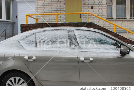 A car parked near a residential building with frozen windows and door handles covered with snow 130408505