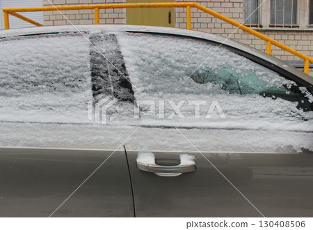 Front door of a vehicle with snow on the window and a frozen door handle 130408506